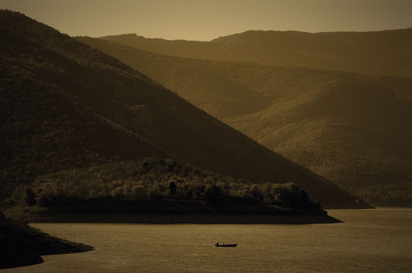 A wooded peninsula on Tikveš Lake near Kavadarci, a single boat on the water